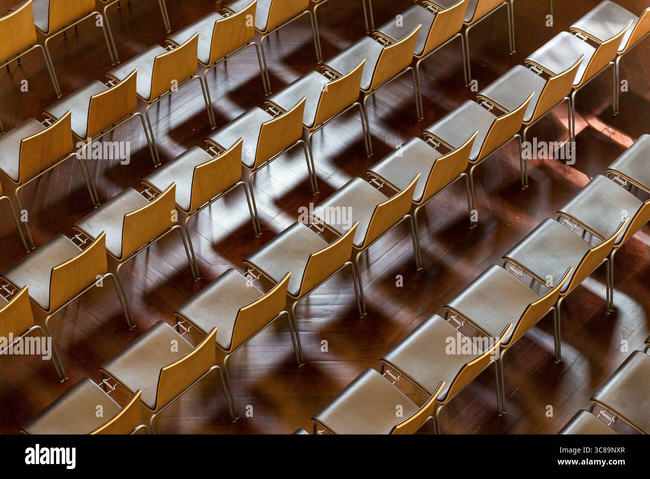 File di sedie in legno con telai metallici su pavimento in legno lucido Foto Stock