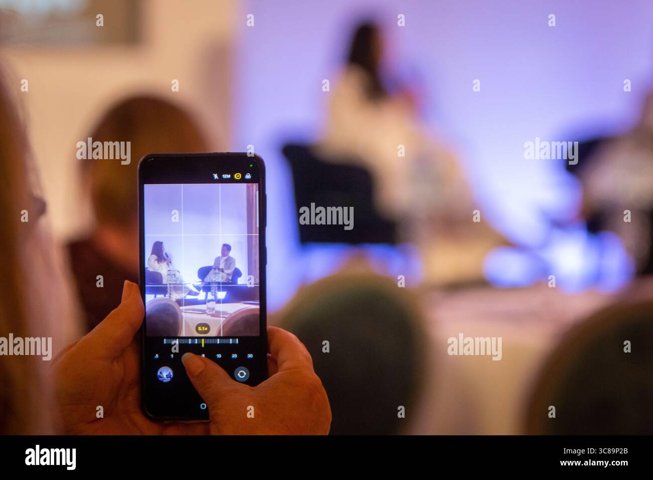 Persona che scatta una foto sul proprio telefono del pannello durante una conferenza Foto Stock