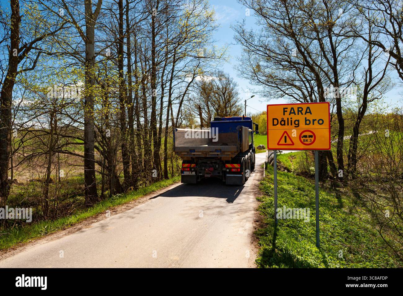 Un camion che passa un cartello con la scritta "ponte pericoloso" Foto Stock Un camion che passa un cartello con la scritta "ponte pericoloso" Foto Stock