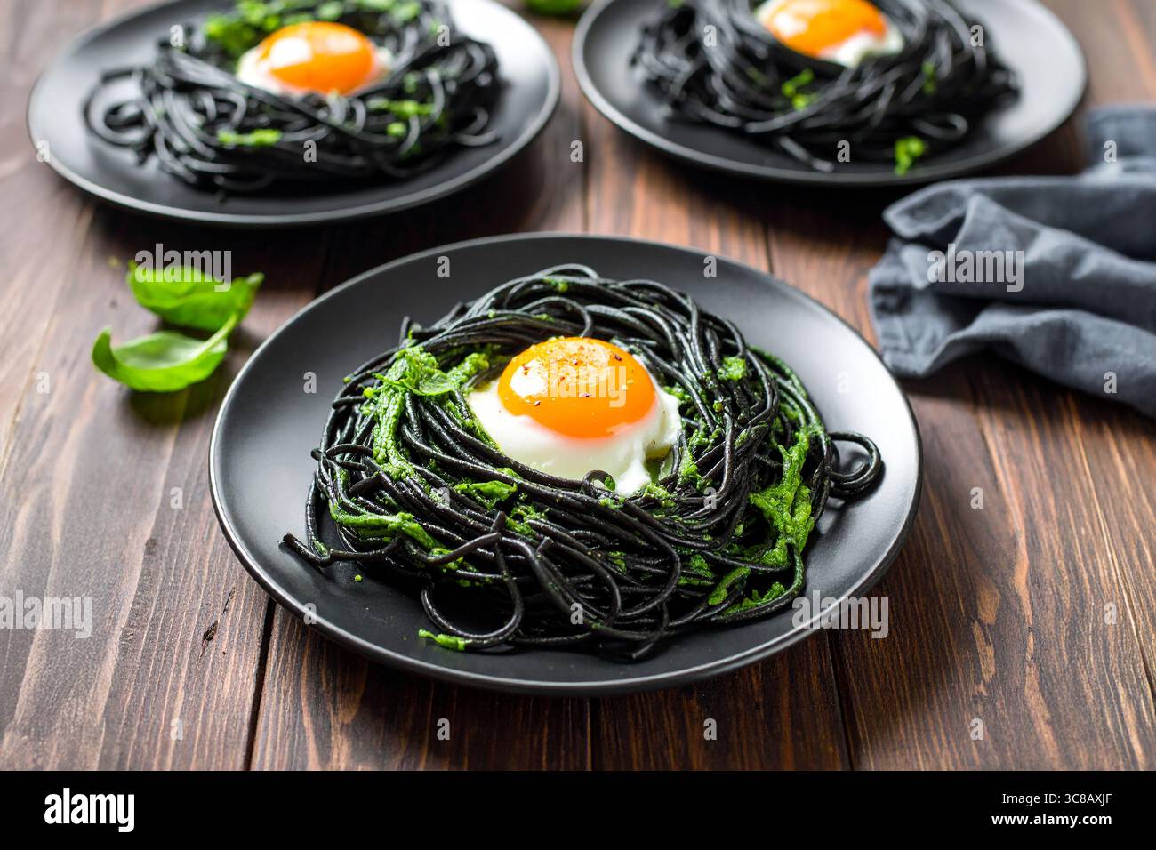 Pasta al nero di calamaro ricoperta da un uovo fritto con il lato del sole, un piatto gourmet di pesce dai sapori ricchi e un fascino visivo unico. Foto Stock