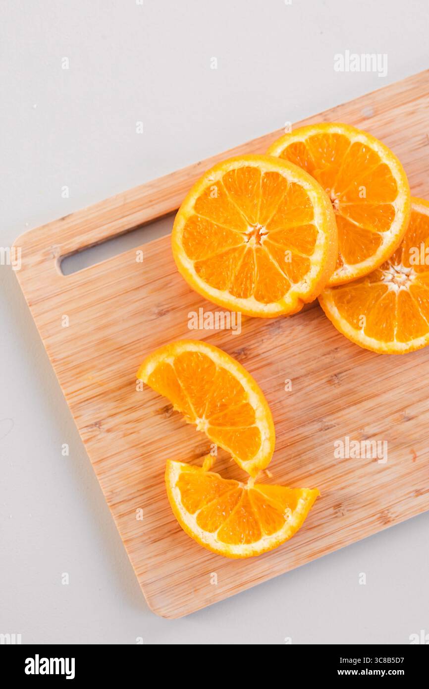 succose fette di arancia disposte su un tagliere di legno con un coltello arancione brillante, concetto di mangiare sano, frutta biologica e preparazione alimentare Foto Stock succose fette di arancia disposte su un tagliere di legno con un coltello arancione brillante, concetto di mangiare sano, frutta biologica e preparazione alimentare Foto Stock