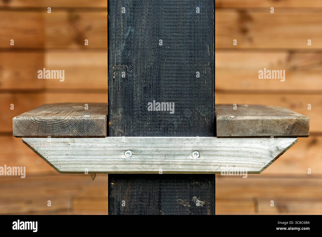 Un ripiano in legno è fissato saldamente a un montante nero all'interno di un'accogliente cabina, con elementi di design rustici e materiali naturali. Foto Stock