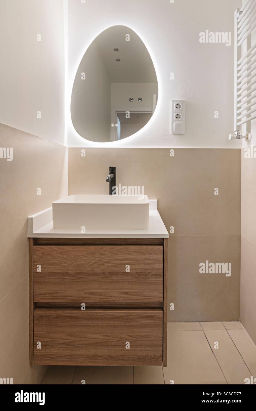 Bagno in stile Spa con lavandino in porcellana su un ripiano in pietra, rubinetti in bronzo e box doccia con pioggia Foto Stock