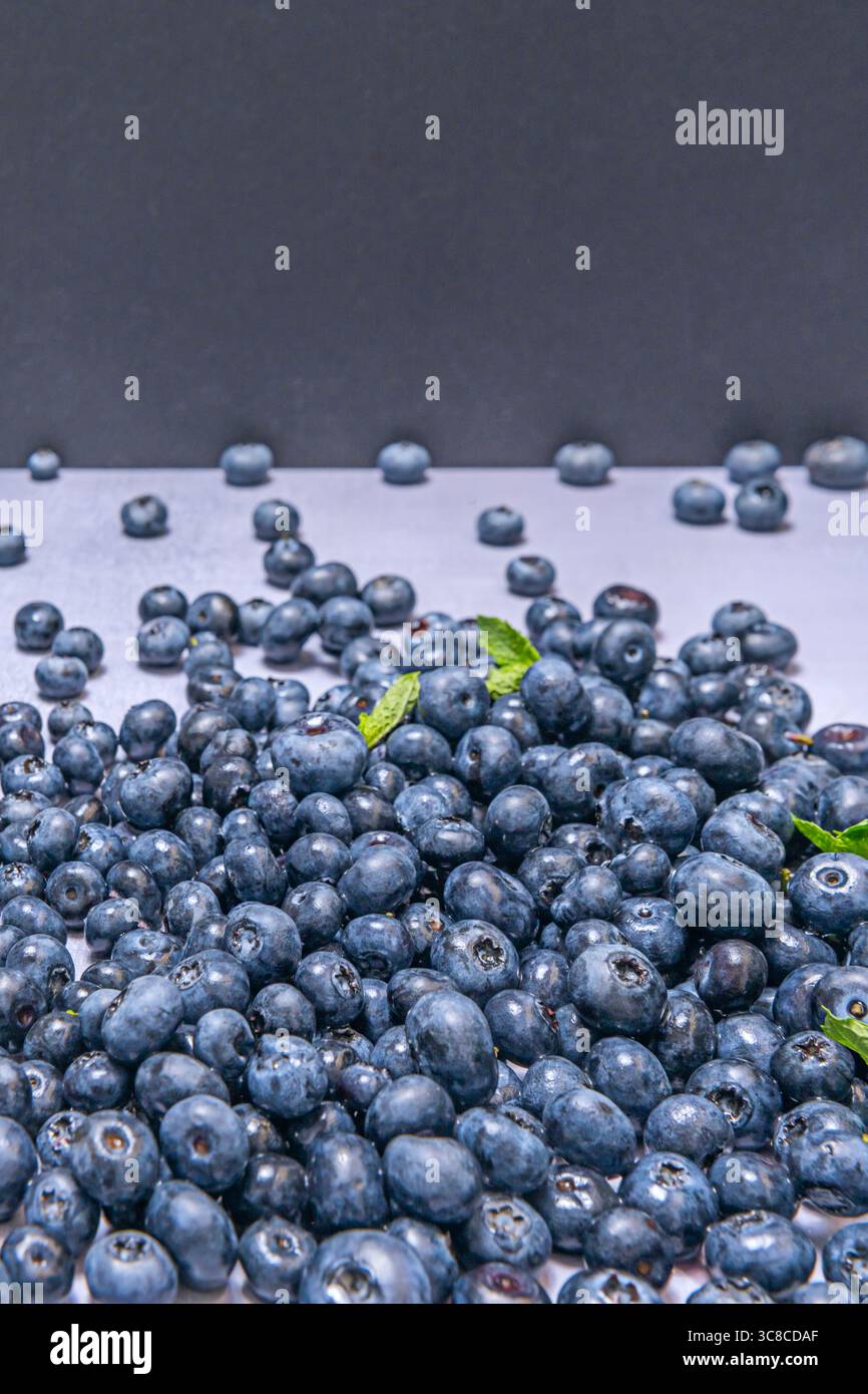 Primo piano di mirtilli appena lavati con una texture perfetta, illuminati da luce naturale che ne esalta la tonalità blu intenso Foto Stock