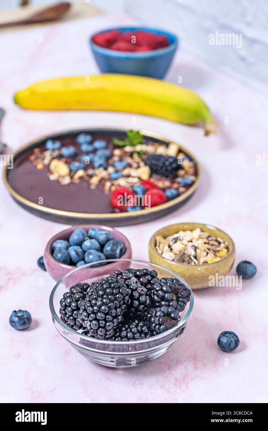 Fotografia minimalista: Frullato di mirtilli e yogurt greco, con una manciata di frutti di bosco accanto su sfondo bianco Foto Stock