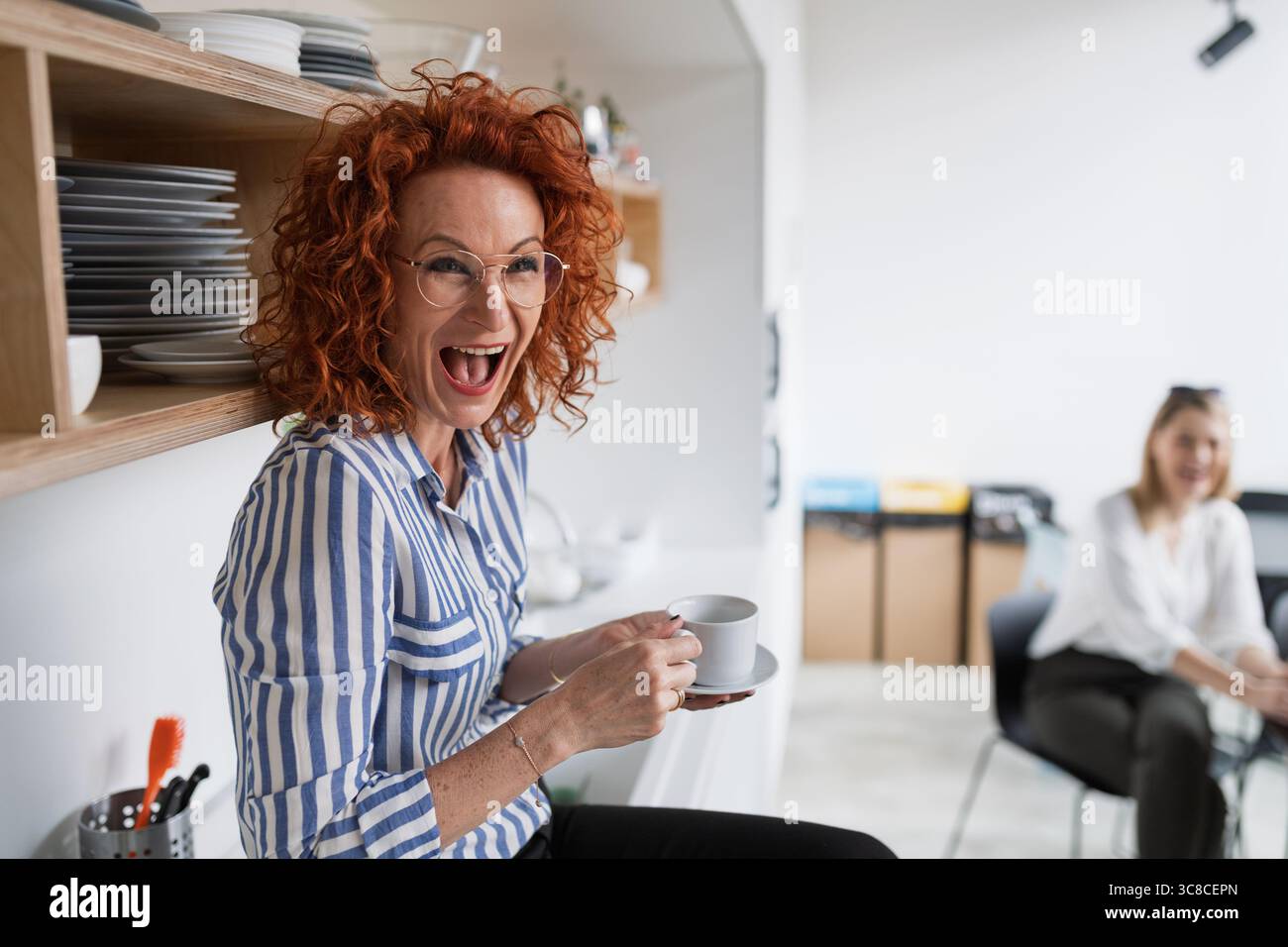 Donna d'affari matura in pausa caffè nella cucina dell'ufficio, che tiene il caffè. Foto Stock