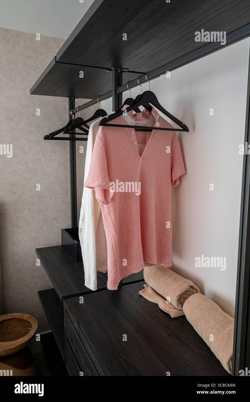 Un armadio nero con una camicia rosa appesa su di esso. La camicia è a righe e ha uno scollo a V. Foto Stock