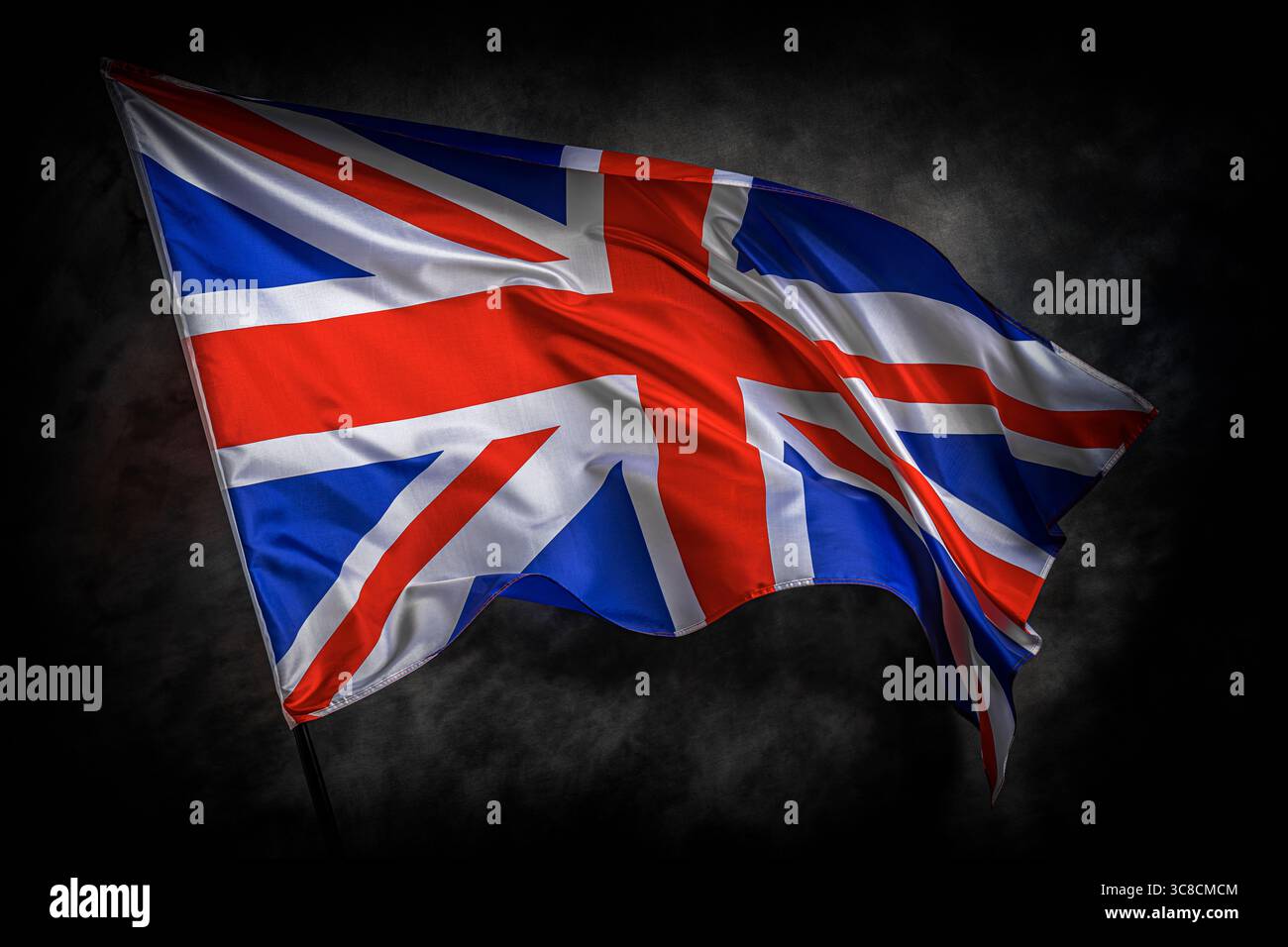 La bandiera del Regno Unito Union Jack ondeggia orgogliosamente su uno sfondo scuro e strutturato Foto Stock