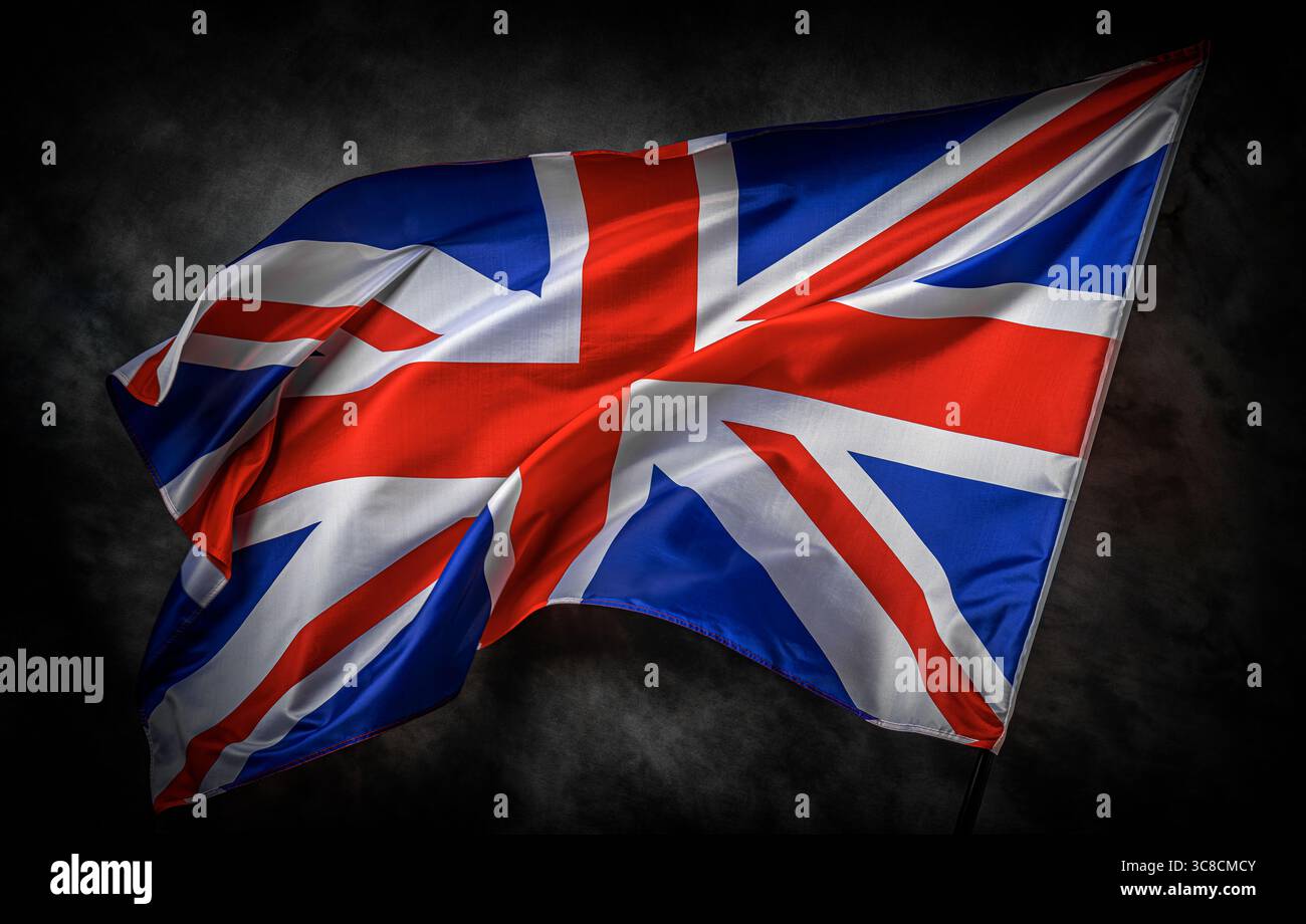 La bandiera del Regno Unito Union Jack ondeggia orgogliosamente su uno sfondo scuro e strutturato Foto Stock