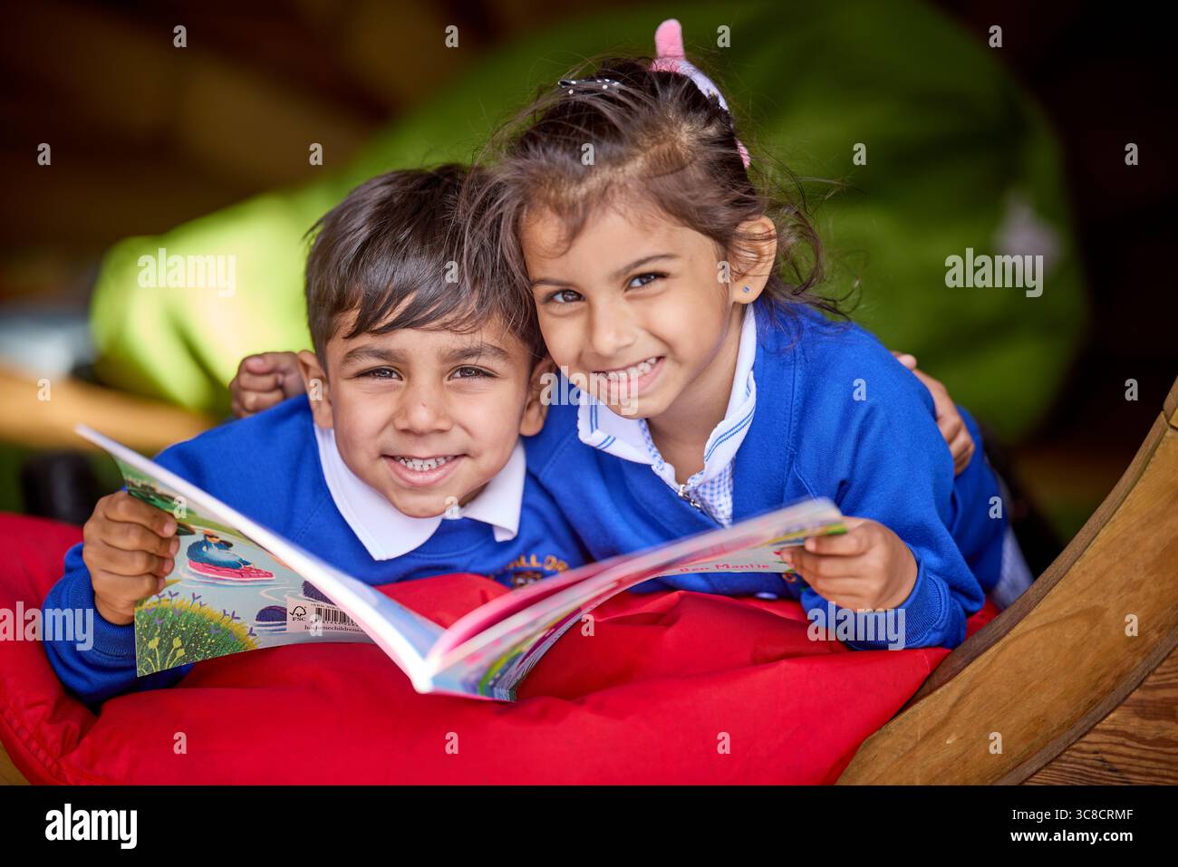 I bambini della scuola elementare si godono un libro di lettura fuori Foto Stock
