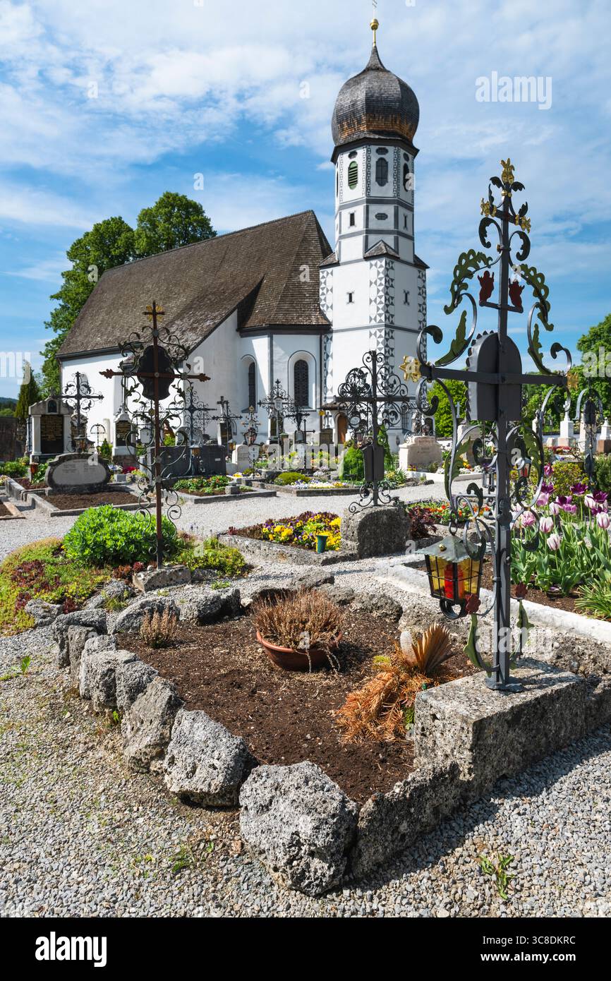 Tombe nel cimitero di fronte alla chiesa bianca di protezione di Santa Maria a Fischbachau, Baviera, Germania Foto Stock