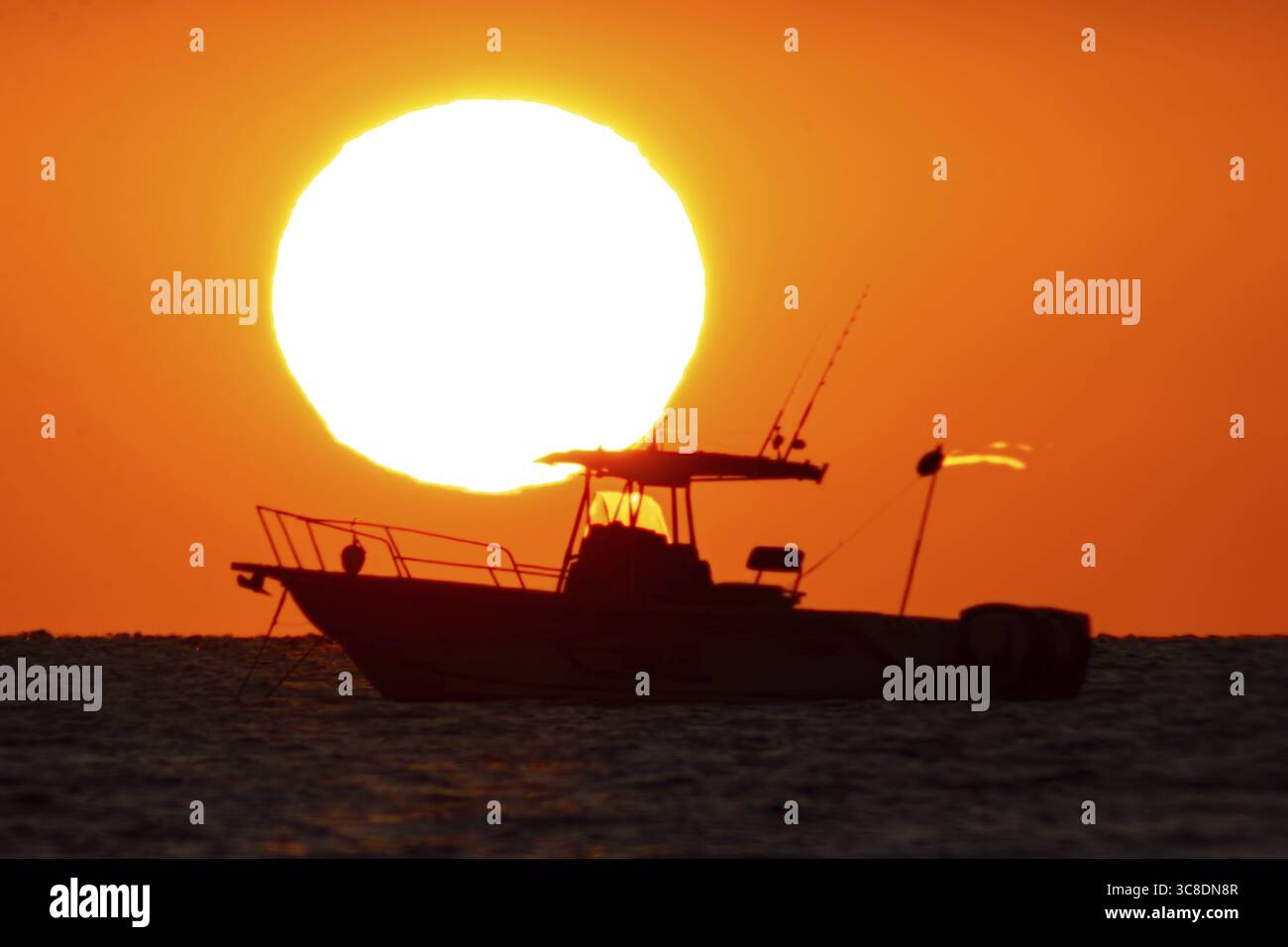 Il sole sorge dietro una barca sulla Costa Rei, un tratto costiero dell'isola mediterranea italiana della Sardegna, Monte Nai, Costa Rei, Sardegna, Italia Foto Stock