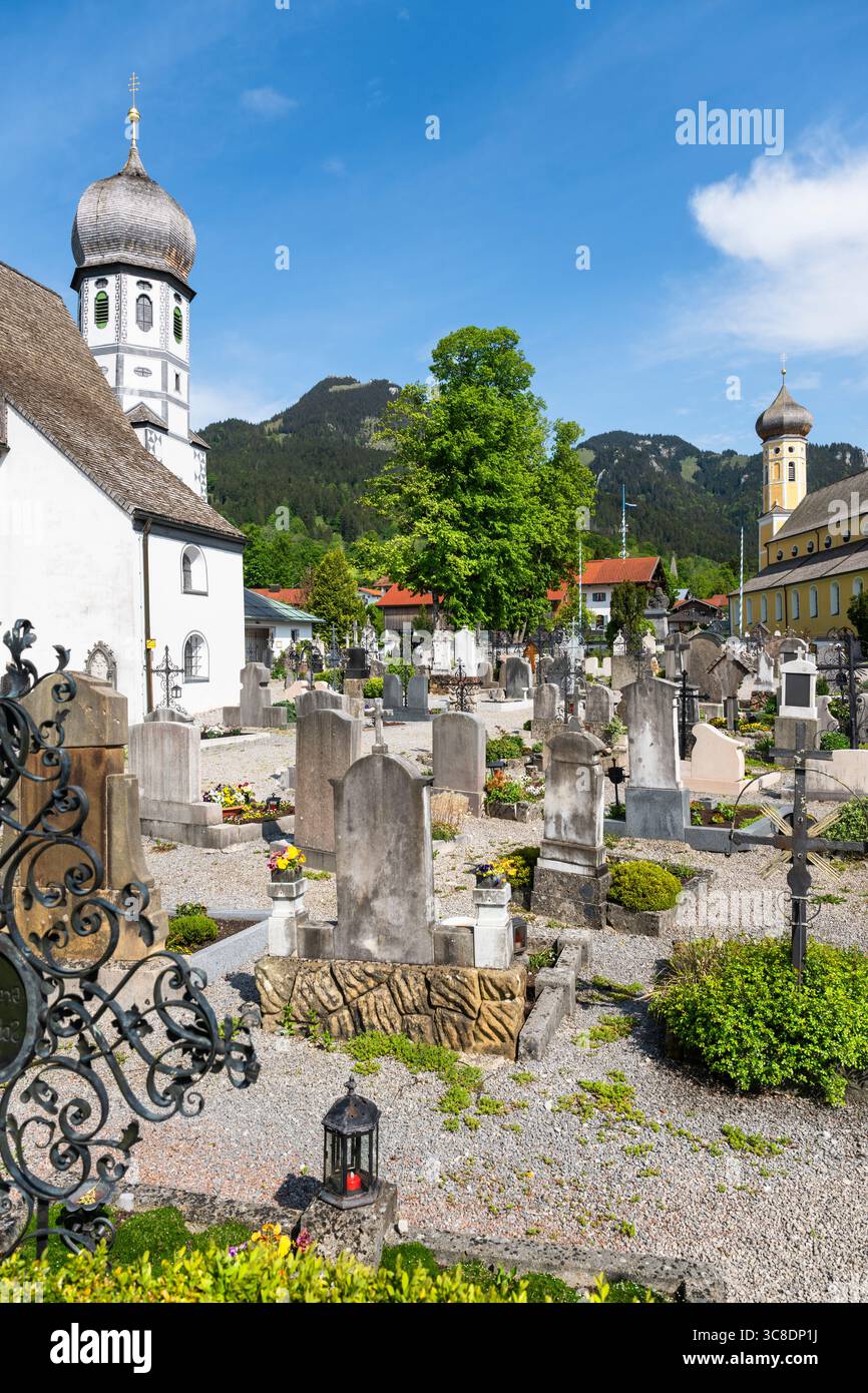 Tombe nel cimitero di fronte alla chiesa bianca di protezione di Santa Maria a Fischbachau, Baviera, Germania Foto Stock
