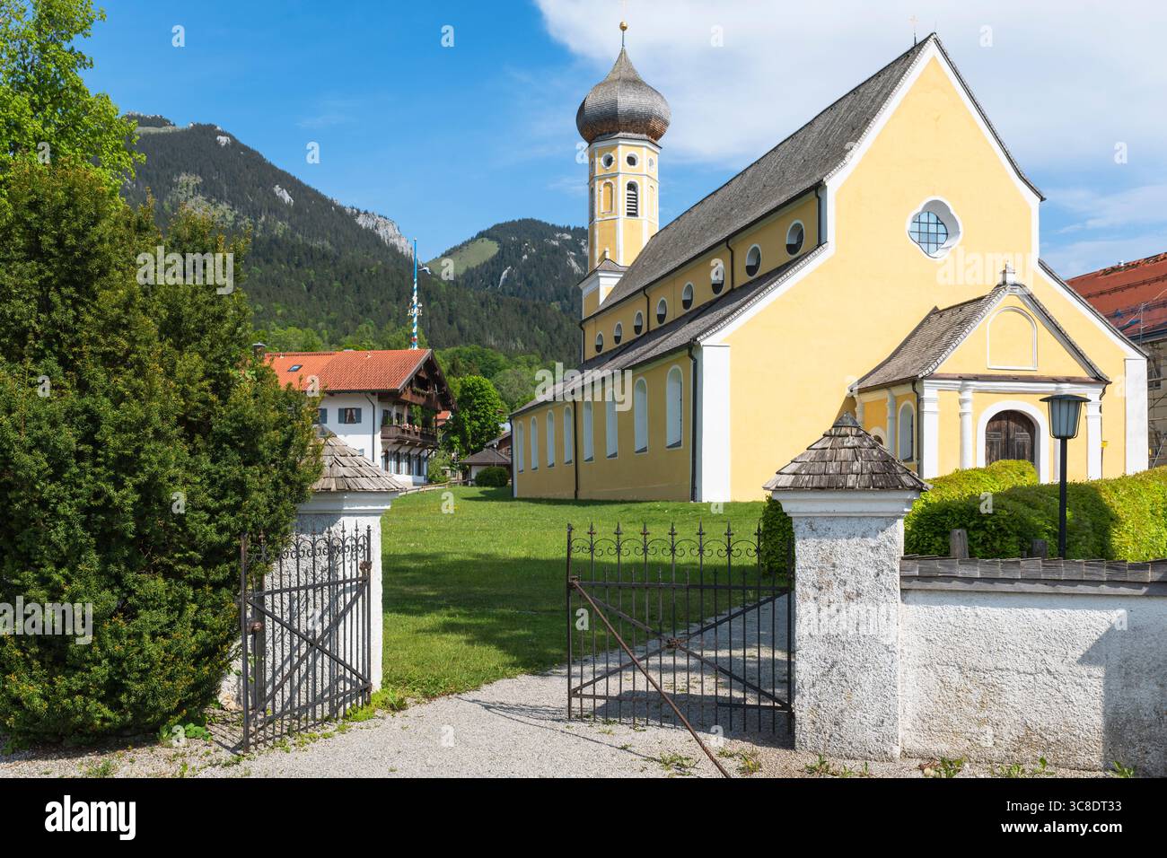 Cancello in ferro battuto all'ingresso del cimitero sulla strada per la chiesa di San Martino a Fischbachau sullo sfondo di una montagna, Baviera, Germania Foto Stock