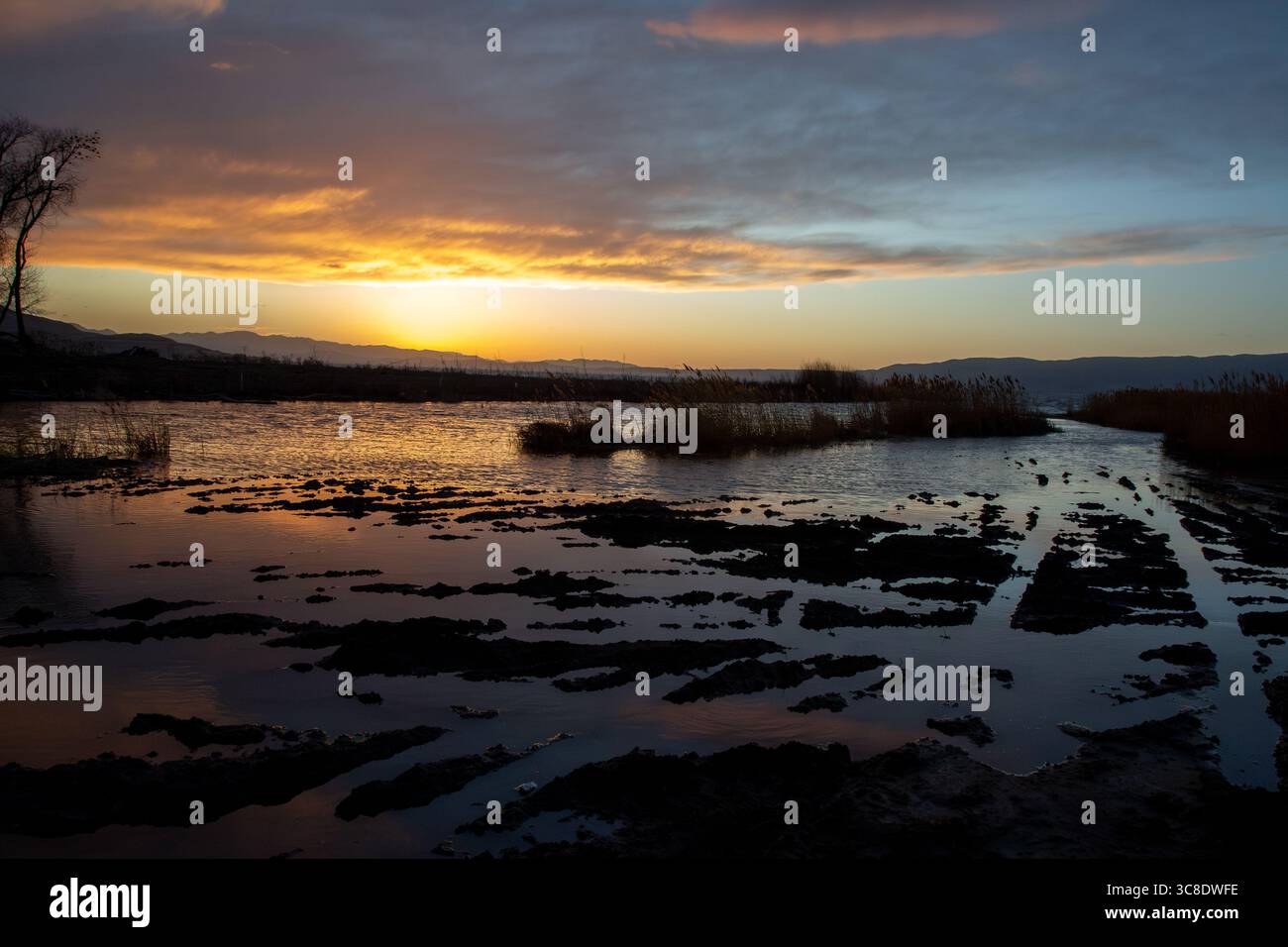Tramonto sul lago Utah con coste scure e riflessi luminosi del cielo Foto Stock