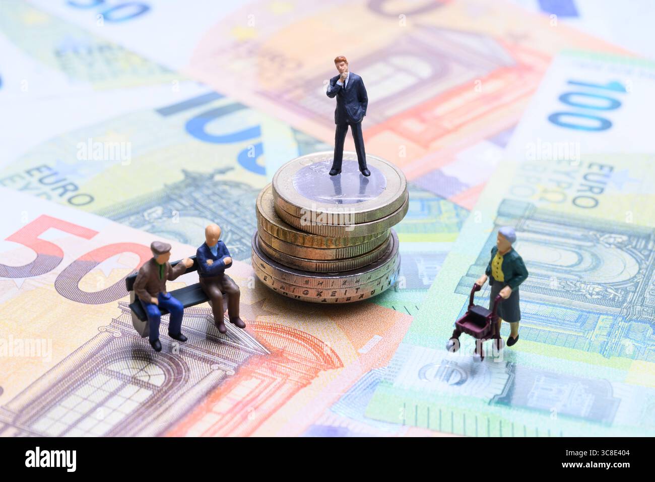 Rentenlücke und Vermögensverteilung Miniaturfiguren auf Geldscheinen und Münzen , Symbolfoto zur finanziellen Ungleichheit zwischen Generationen: Ein Geschäftsmann steht auf einem Stapel Euromünzen, während zwei Rentner auf einer Bank sitzen und eine Seniorin mit Rollator vorbeigeht. Die Szene aus Miniaturfiguren auf Euroscheinen verdeutlicht das Spannungsfeld zwischen Altersarmut, Pflegebedürftigkeit und Kapitalanhäufung. *** Distribuzione del divario pensionistico e della ricchezza cifre in miniatura su banconote e monete , foto simbolica della disuguaglianza finanziaria tra generazioni Un uomo d'affari si erge su una pila Foto Stock