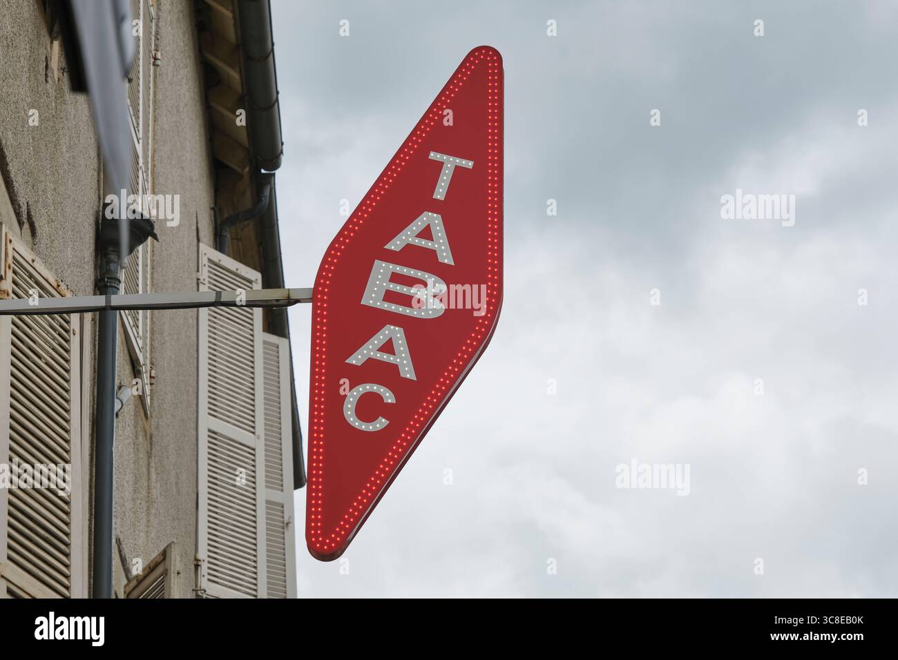 Cartellone rosso a forma di diamante inclinato con la parola tabac bianco e neon sopra un negozio a Saint-Céré Lot Occitanie, Francia meridionale. Foto Stock