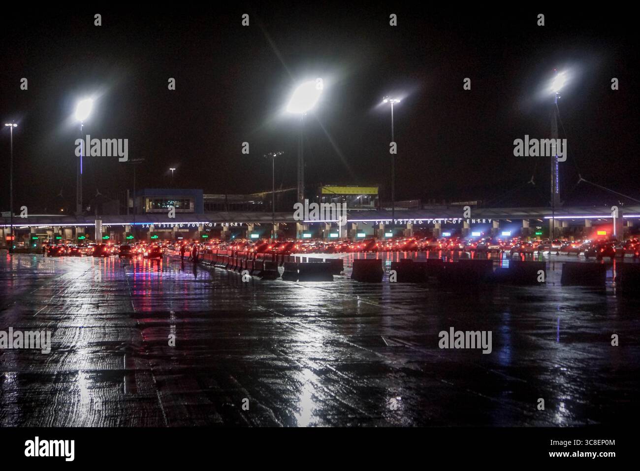 Vista notturna del valico di frontiera di San Ysidro, Tijuana, un popolare punto di migrazione, con auto allineate al confine tra Stati Uniti e Messico Foto Stock