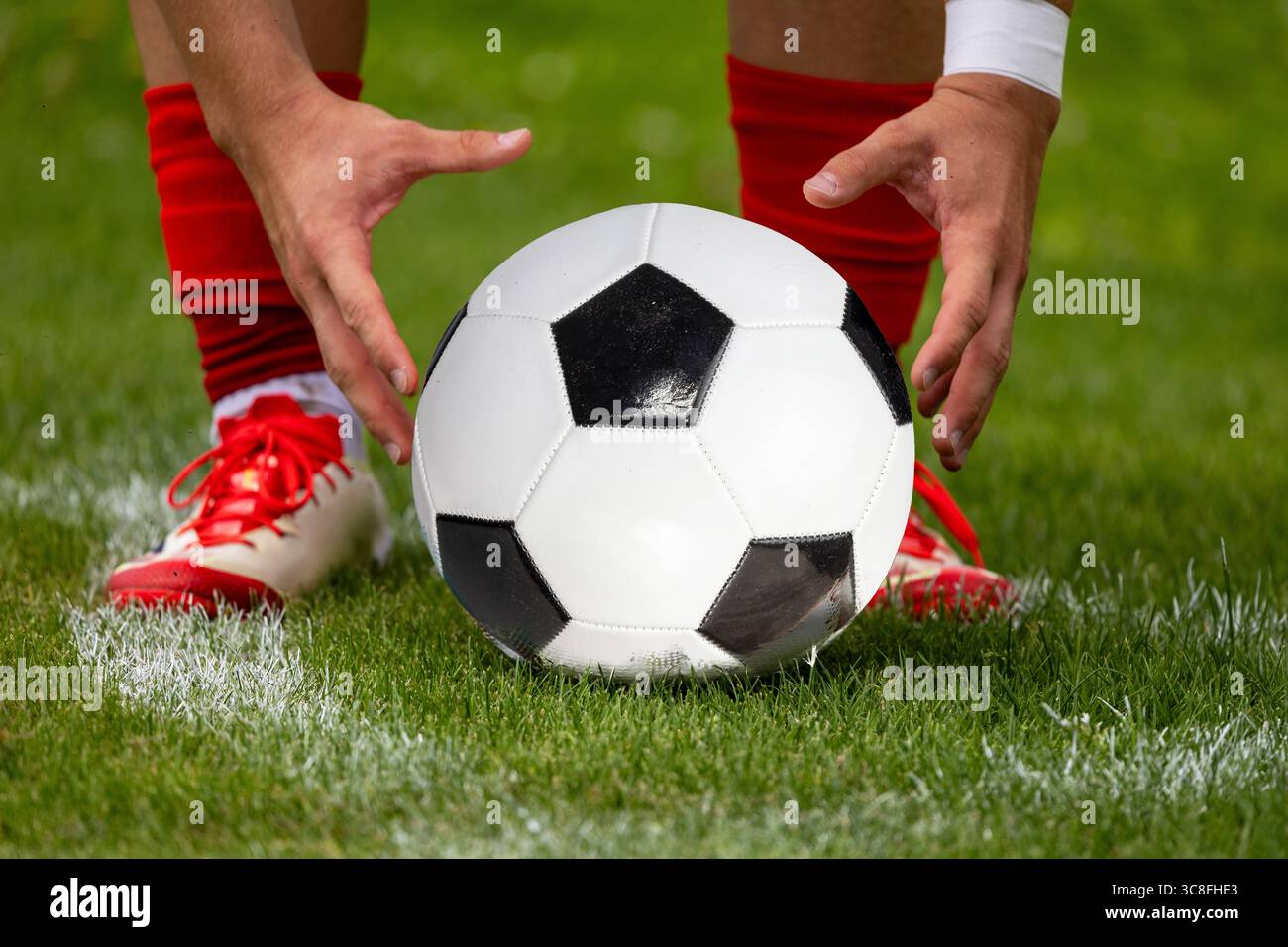 (Montaggio fotografico; palla sostituita) il calciatore prepara la palla per un calcio d'angolo Foto Stock