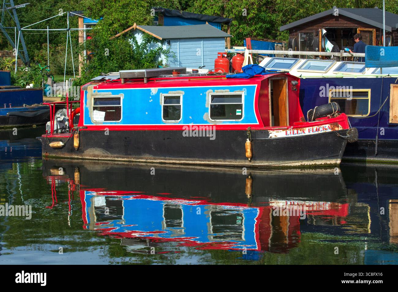 Chiatta blu e rossa, fiume Lee, canale di Lea Valley, Londra, Inghilterra. La proprietà delle imbarcazioni strette è aumentata a causa del costo della vita. Foto Stock
