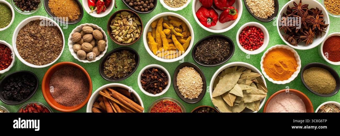 Un variopinto assortimento di spezie ed erbe fresche e profumate, visualizzato su un morbido sfondo verde, che cattura una brillante essenza culinaria, striscione Foto Stock