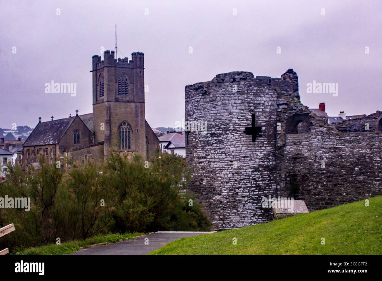 Resti di una torre del castello medievale di Aberystwyth con la chiesa di San Michele sullo sfondo in una mattina fredda e nebbiosa. Foto Stock