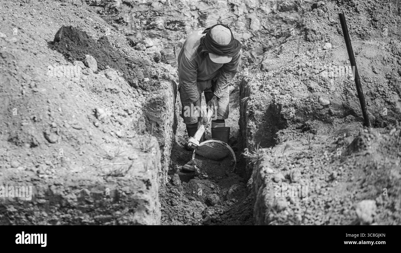 Un lavoratore scava le fondamenta dell'edificio, documentando un processo chiave per la creazione di una costruzione durevole. Foto Stock