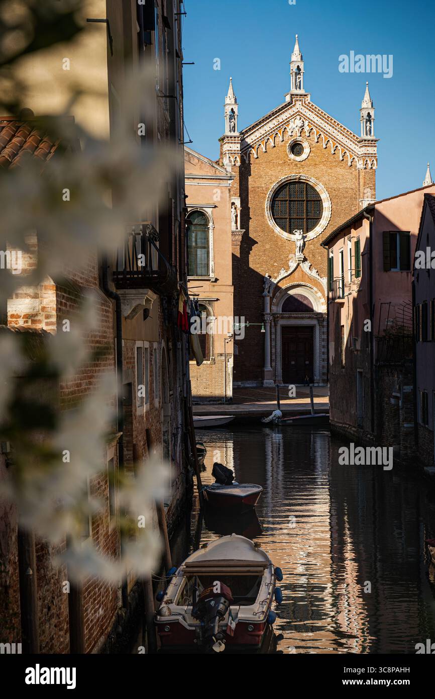 Una chiesa veneziana nascosta incastonata in uno stretto vicolo, che rivela il fascino senza tempo dell'architettura sacra italiana. Foto Stock