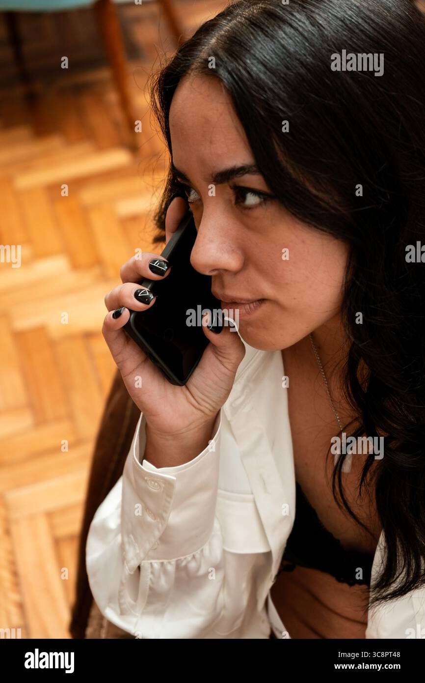 Giovane donna d'affari che parla con lo smartphone, gestisce il lavoro in remoto dall'ufficio domestico Foto Stock