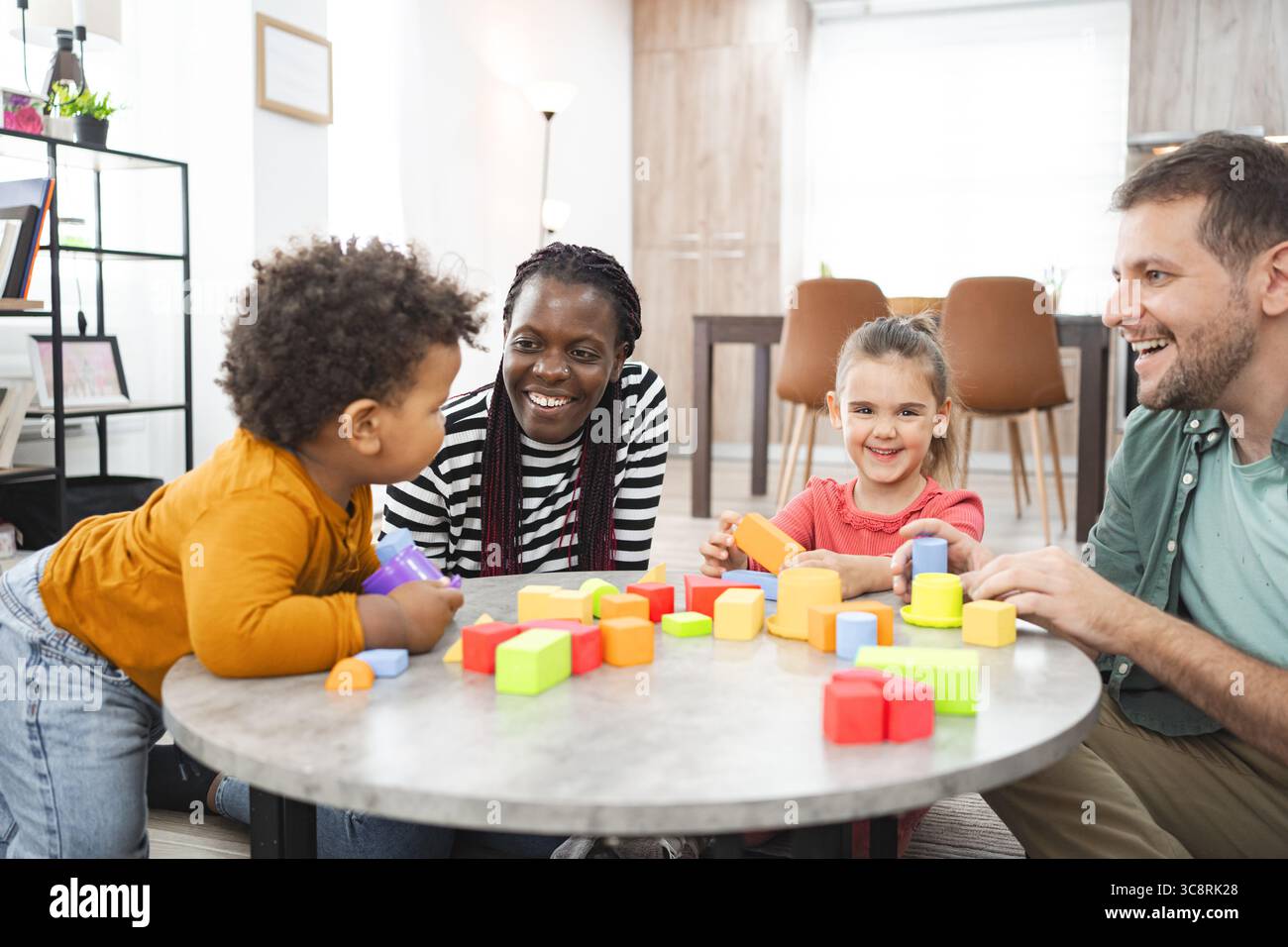 Famiglia multirazziale che gioca con blocchi colorati al chiuso Foto Stock