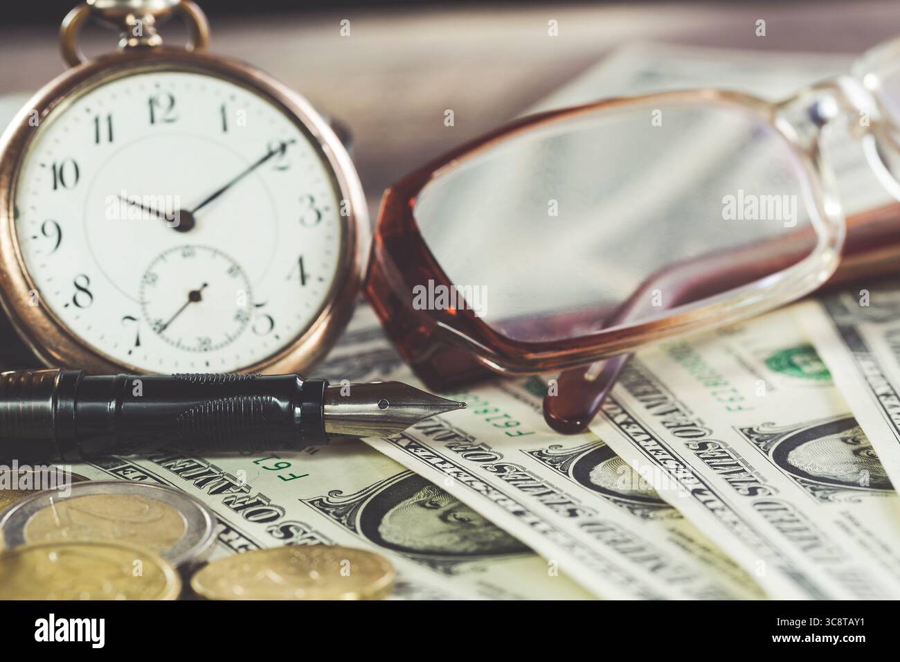 Design finanziario in stile vintage con occhiali, banconote da un dollaro, orologio retrò, monete e penna stilografica. Foto Stock