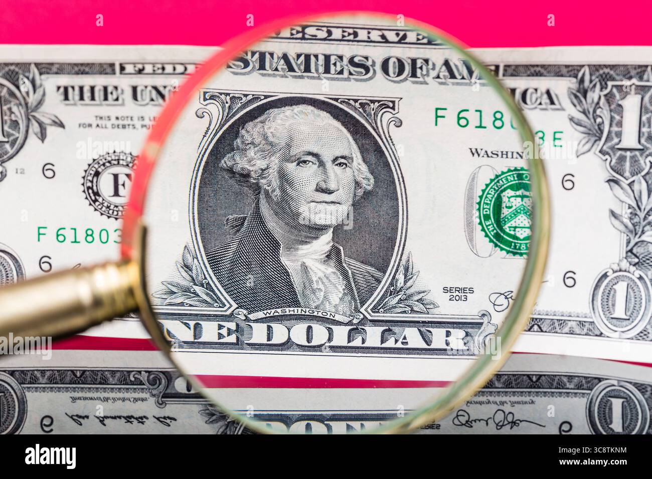 Banconota in dollari americani attraverso una lente d'ingrandimento su un bel fondo rosso. Foto Stock
