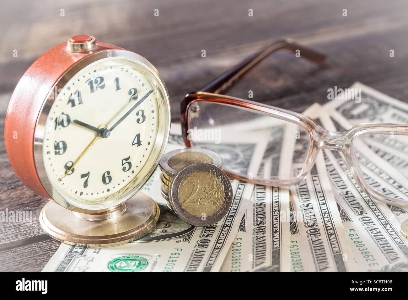 Il tempo è un concetto di finanza monetaria con vecchi orologi d'epoca, banconote da un dollaro, occhiali e monete in euro. Foto Stock