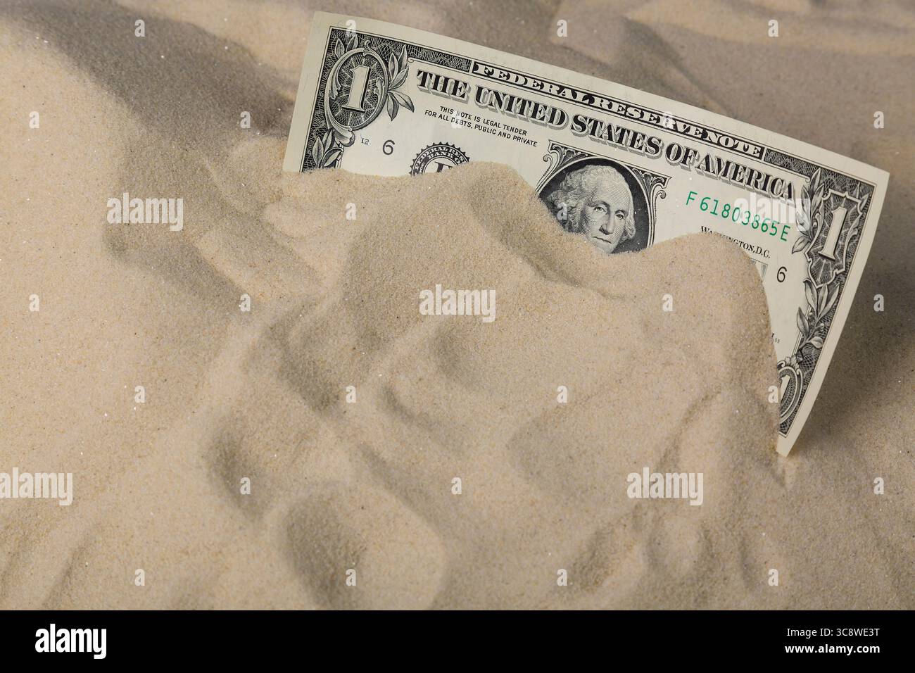Concetto finanziario. Una banconota da un dollaro nella sabbia. Foto Stock