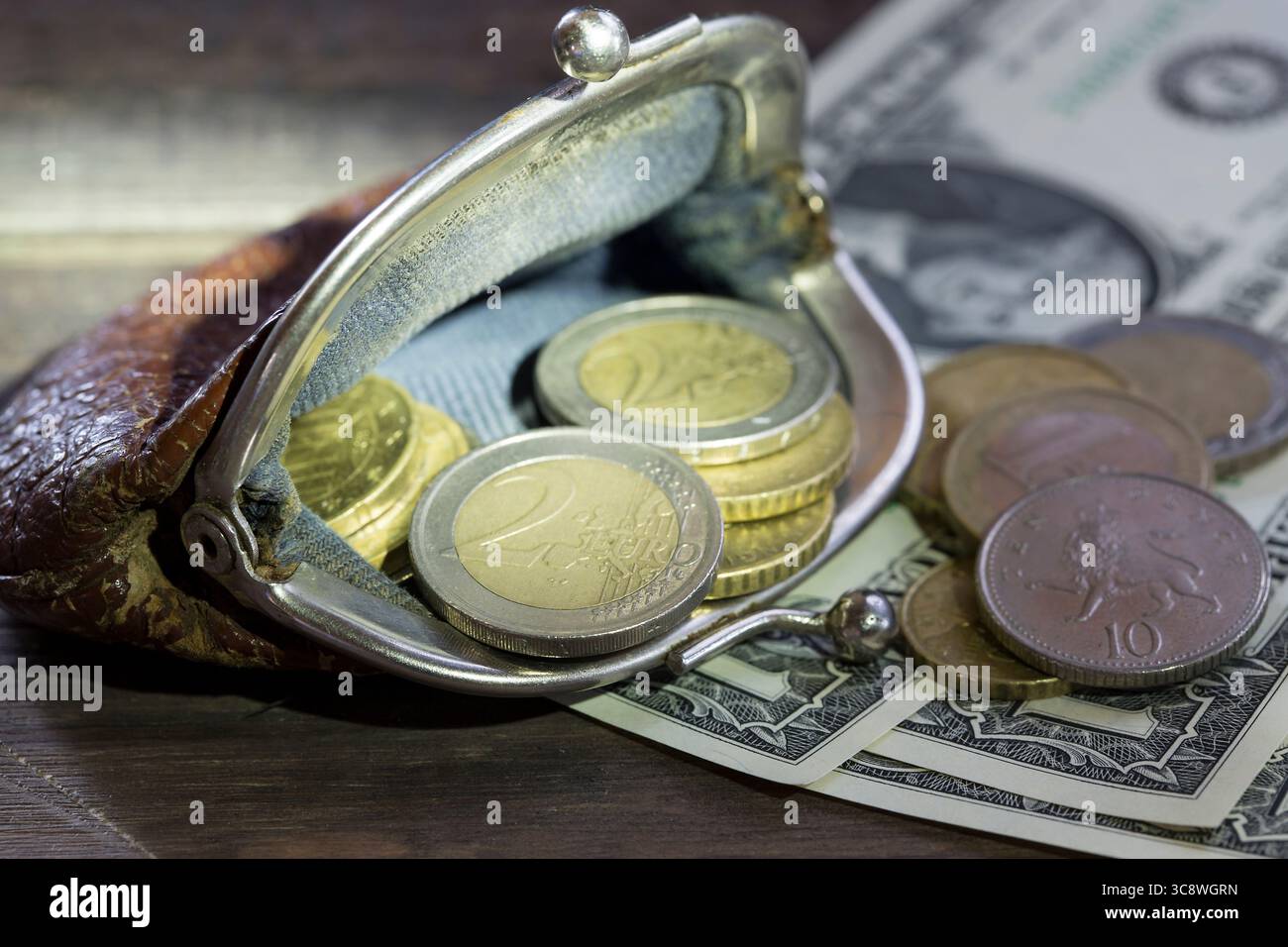 Concetto finanziario. Portafoglio vintage con monete in euro e banconote in dollari su sfondo in legno. Foto Stock