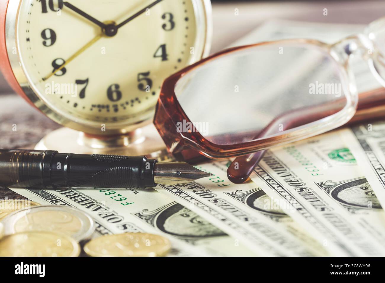 Design finanziario in stile vintage con occhiali, banconote da un dollaro, orologio retrò, monete e penna stilografica. Foto Stock
