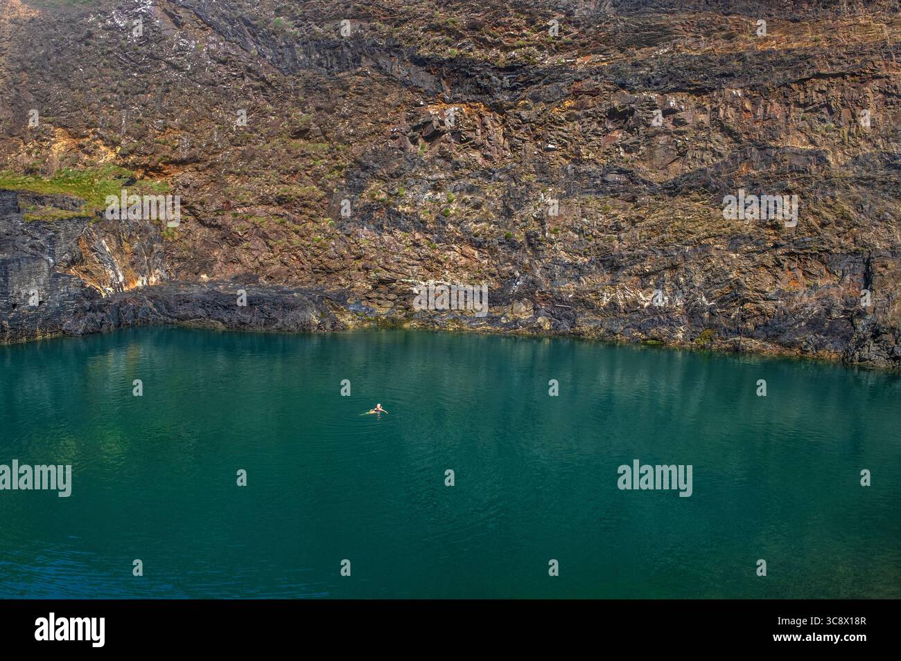 Nuotatore solitario alla Blue Lagoon di Abereiddy, Pembrokeshire, Galles occidentale, Regno Unito Foto Stock