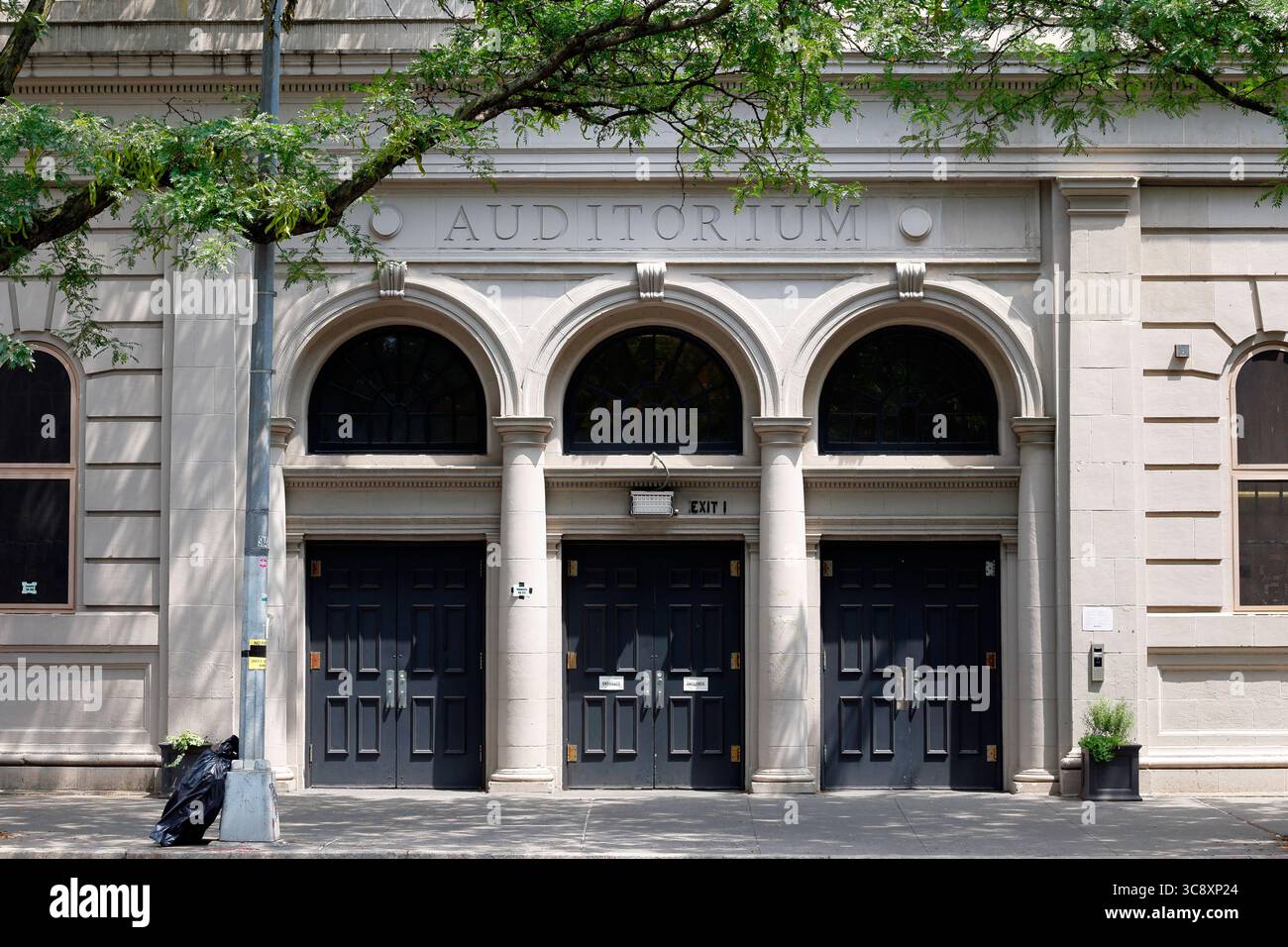 Un ingresso all'edificio con le parole Auditorium su tre porte ad arco della scuola pubblica di New York 3 Charrette School nel West Village di Manhattan Foto Stock