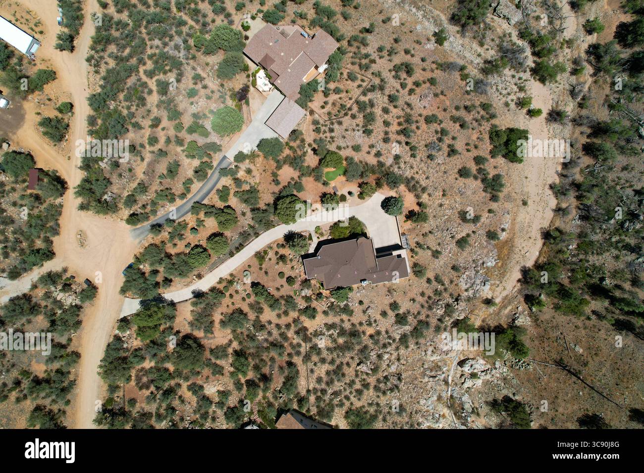Una grande casa si trova su una collina, circondata da alberi e rocce Foto Stock