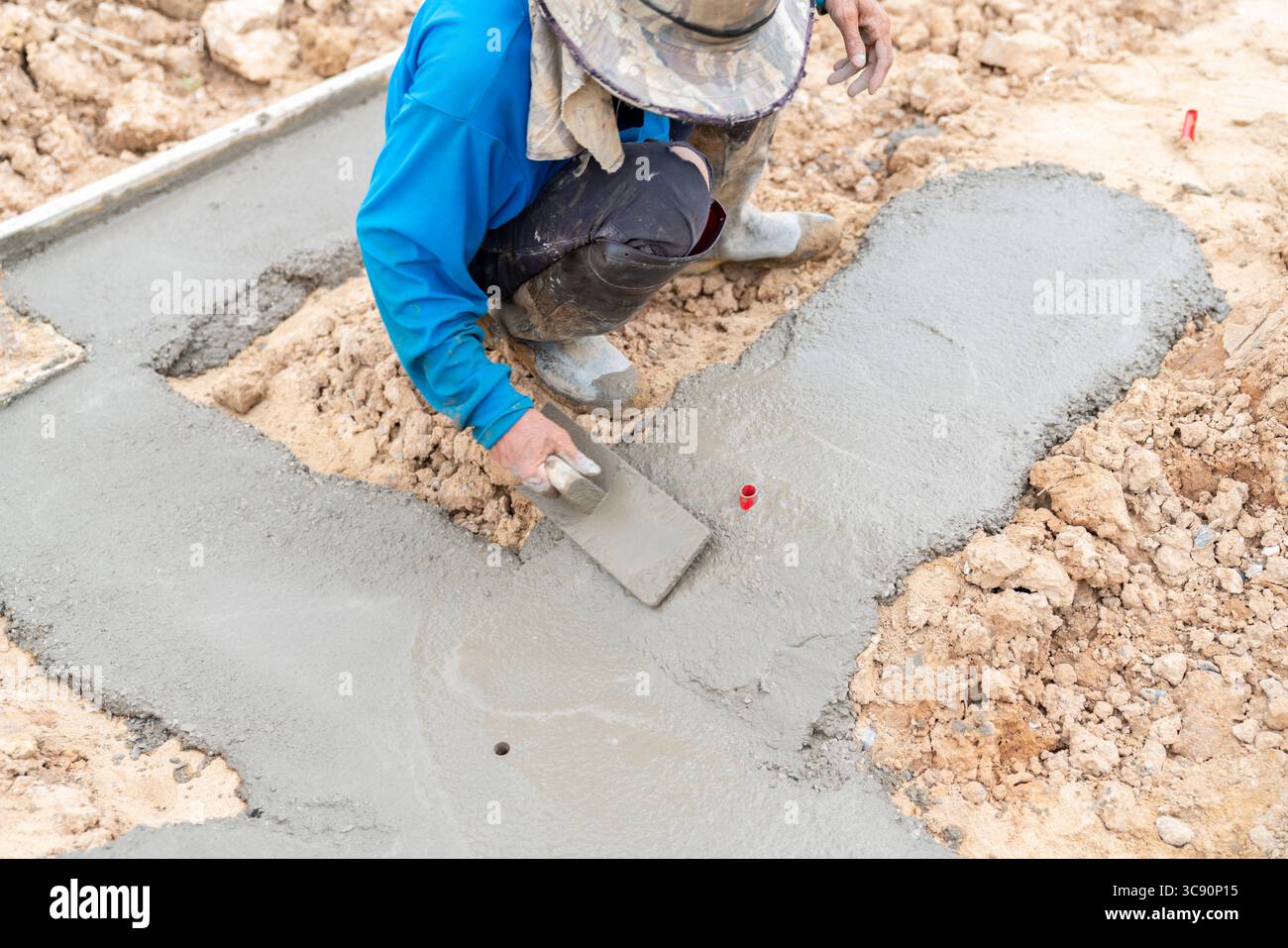 Un lavoratore sta lavorando sul calcestruzzo magro per ottenere una superficie piana e uniforme. Foto Stock