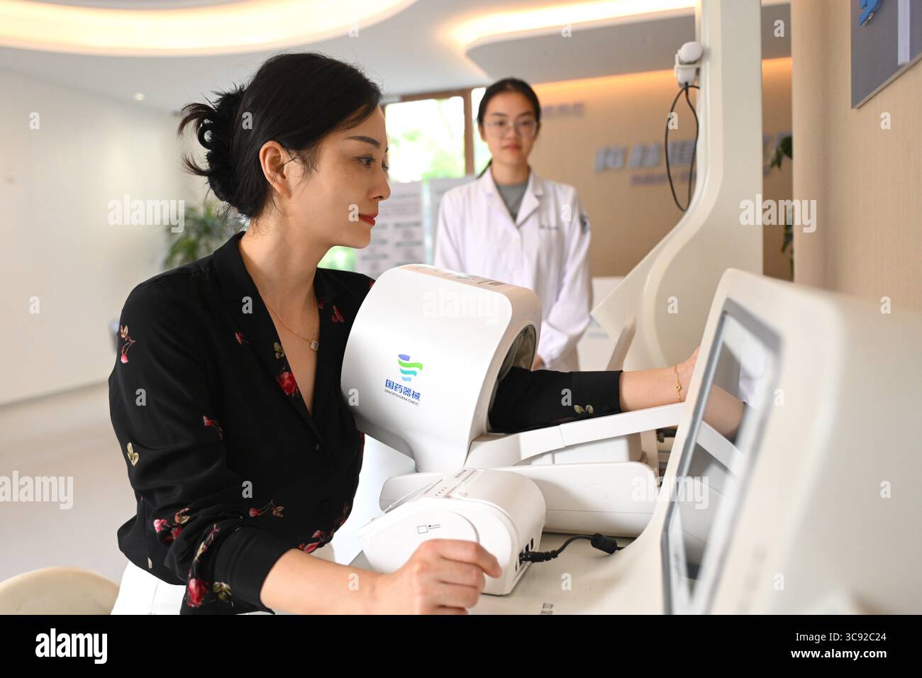 (250805) -- HANGZHOU, 5 agosto 2025 (Xinhua) -- Una donna misura la pressione sanguigna da sola in una stazione sanitaria intelligente del villaggio di Meilin nel distretto di Xiaoshan di Hangzhou, nella provincia di Zhejiang della Cina orientale, il 4 agosto 2025. Meilin, che è stato a lungo un villaggio modello per lo sviluppo rurale, ha esplorato attivamente modi per ridurre l'inquinamento e le emissioni di carbonio negli ultimi anni. Attraverso una serie di misure, come la promozione di progetti fotovoltaici sui tetti, la costruzione di terreni agricoli intelligenti e stazioni di ricarica e stoccaggio fotovoltaiche integrate, l'energia pulita viene ampiamente adottata in questo ambito, iniettando l'impe verde Foto Stock