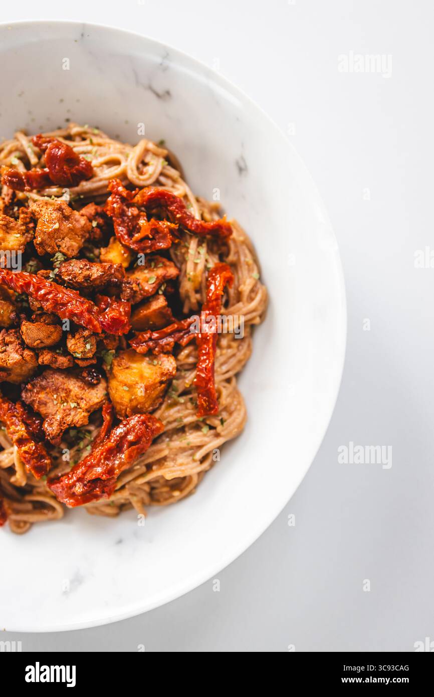 una nutriente ciotola di spaghetti soba ricoperti da pezzi di teriyaki tofu e pomodori secchi, ideale per pasti sani, a base vegetale e prediabete Foto Stock una nutriente ciotola di spaghetti soba ricoperti da pezzi di teriyaki tofu e pomodori secchi, ideale per pasti sani, a base vegetale e prediabete Foto Stock