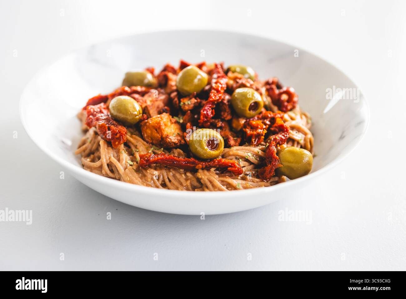 una nutriente ciotola di spaghetti di soba ricoperti da pezzi di teriyaki tofu, pomodori secchi e olive verdi — ideale per sani, a base vegetale e prediabet Foto Stock una nutriente ciotola di spaghetti di soba ricoperti da pezzi di teriyaki tofu, pomodori secchi e olive verdi — ideale per sani, a base vegetale e prediabet Foto Stock