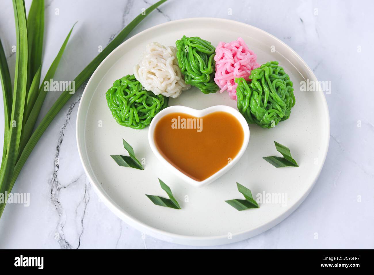 Kue Putu Mayang, una tradizionale torta indonesiana al vapore che presenta filamenti simili a noodle realizzati con farina di riso e salsa di zucchero di palma (kinca). Foto Stock