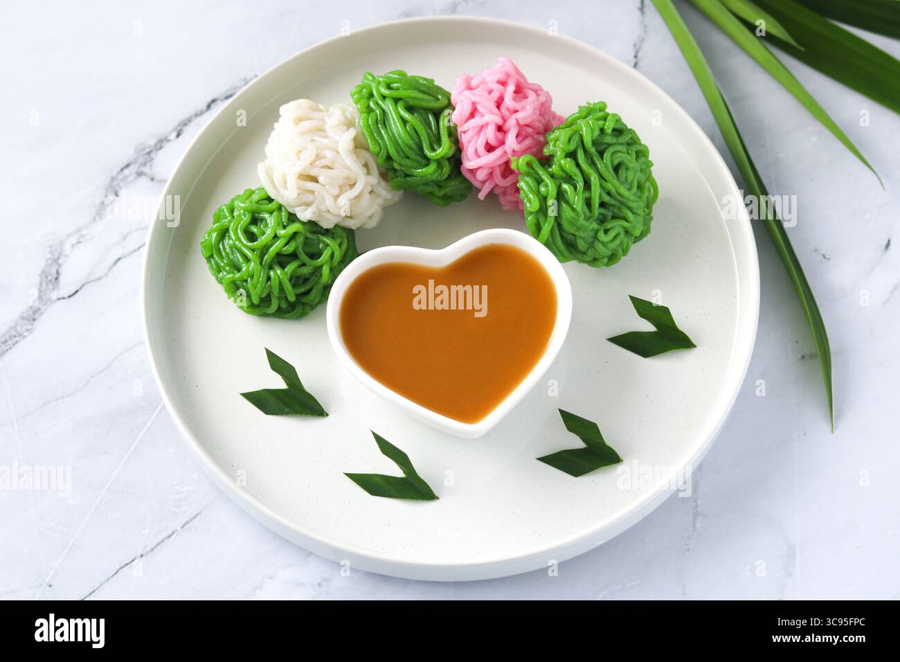 Kue Putu Mayang, una tradizionale torta indonesiana al vapore che presenta filamenti unici simili a tagliatelle, realizzati con farina di riso e salsa di zucchero di palma (kinca). Foto Stock