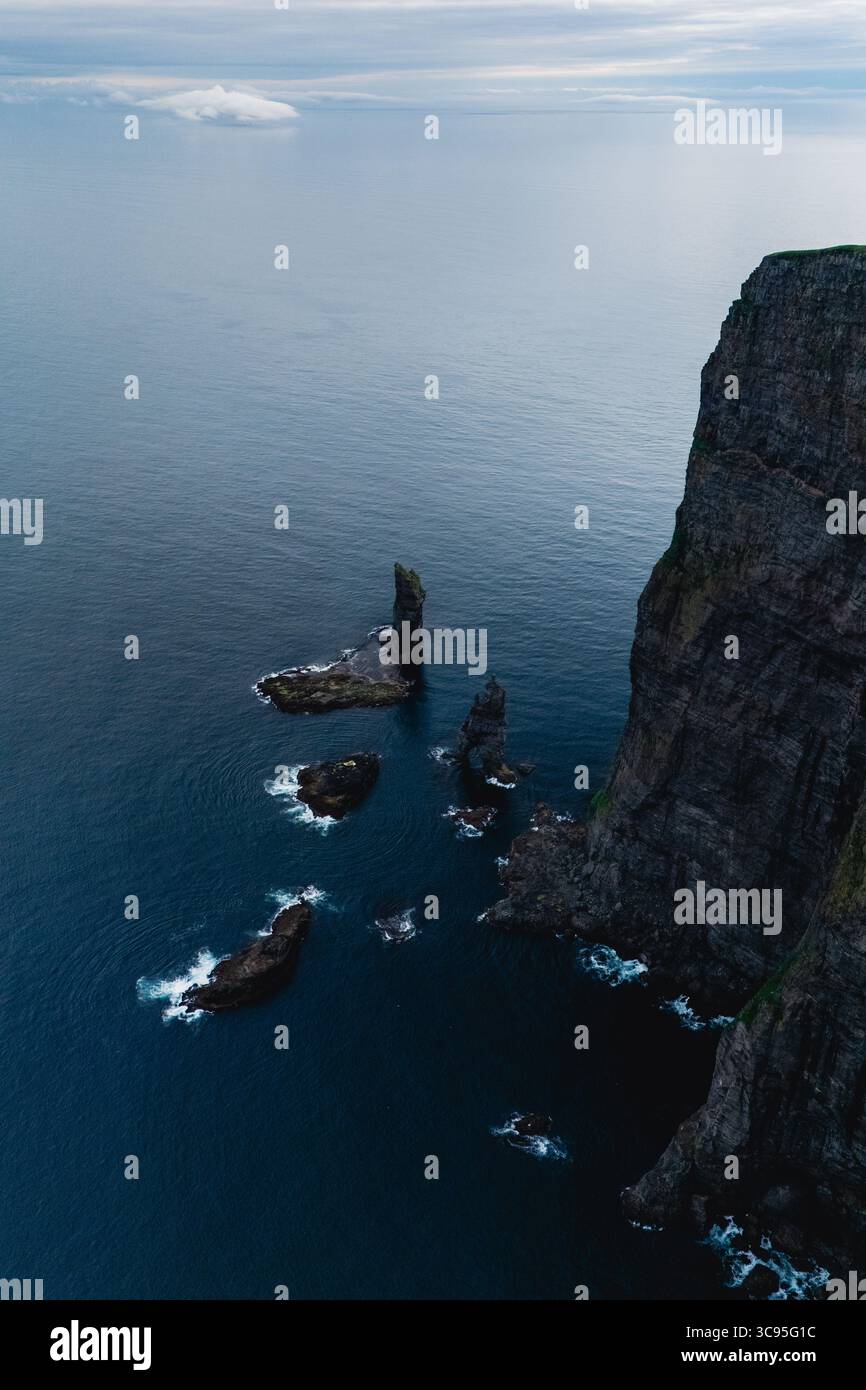 Le maestose scogliere si innalzano drammaticamente dalle tranquille acque atlantiche delle Isole Faroe, adornate da formazioni rocciose uniche. Scogliere Risin OG Kellingin Foto Stock