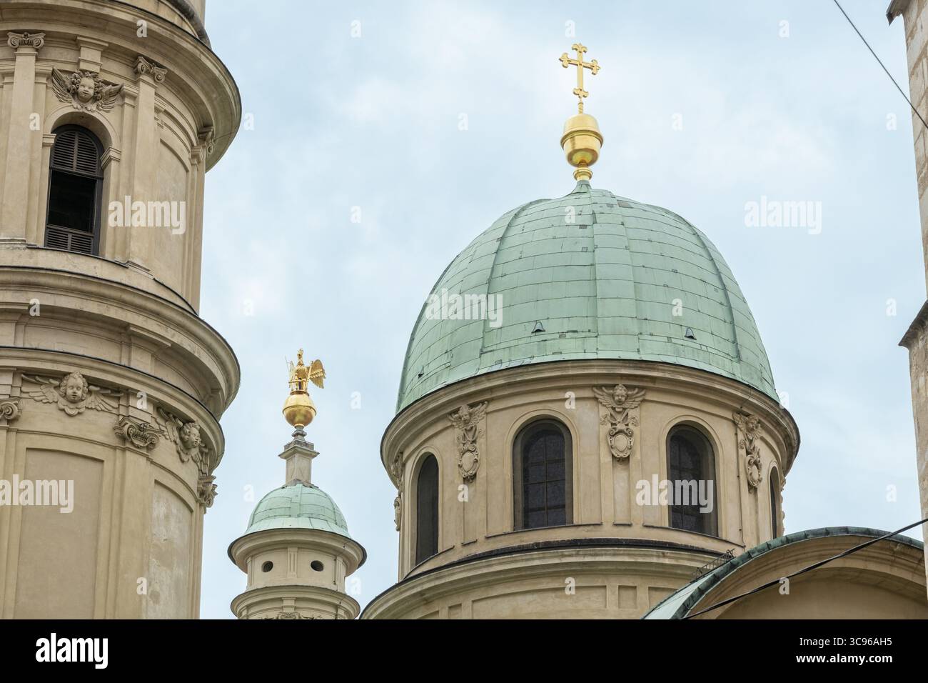 Vista della croce dorata in cima alla cupola del Mausoleo, un faro contro il cielo tenue, incorniciato dall'intricata architettura di Graz, Stiria, Austria. Foto Stock