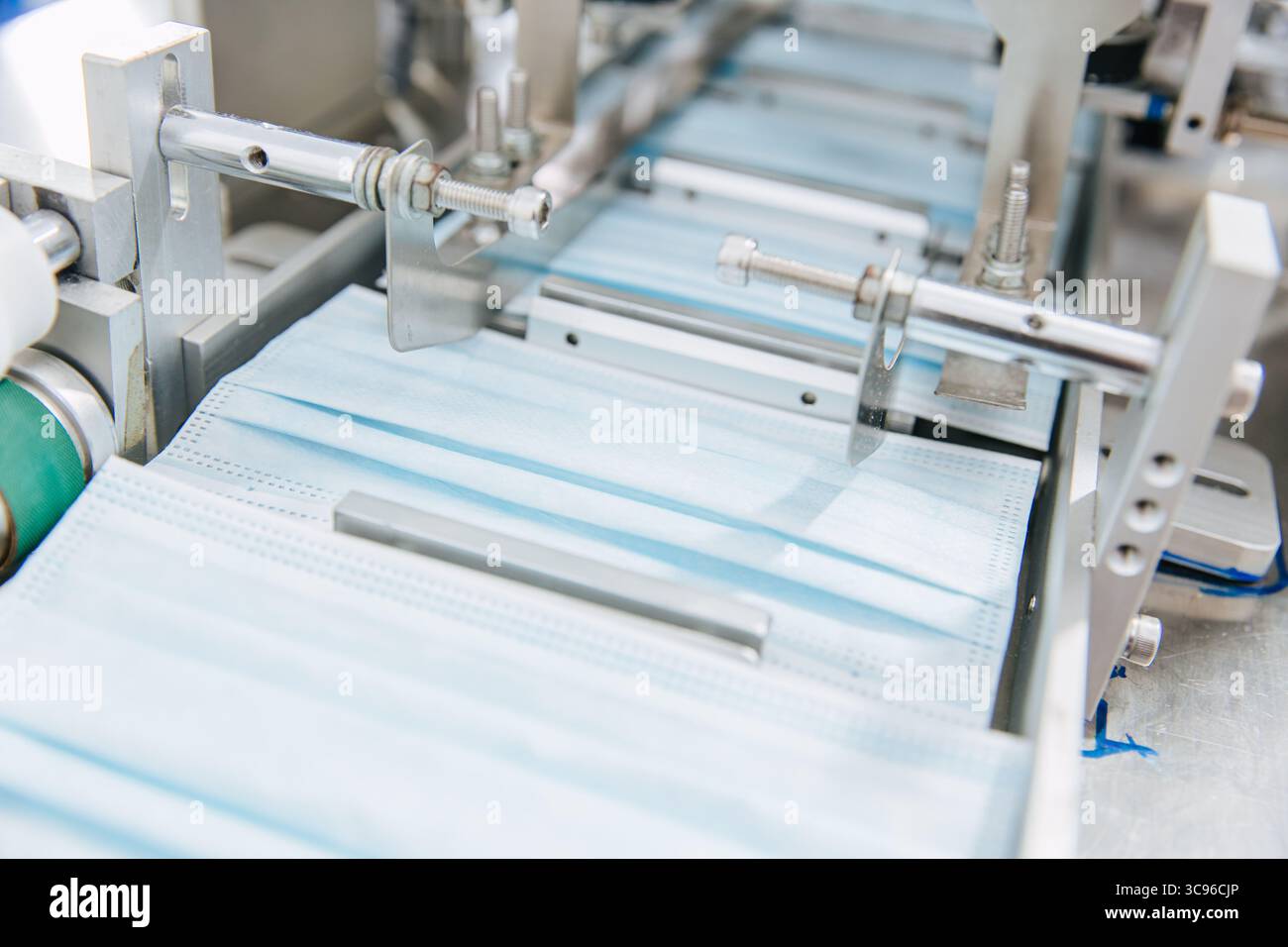 Fabbrica di maschere facciali, linea di produzione di impianti di maschere chirurgiche, rullo nastro trasportatore macchina per primo piano in fabbrica di igiene pulita Foto Stock