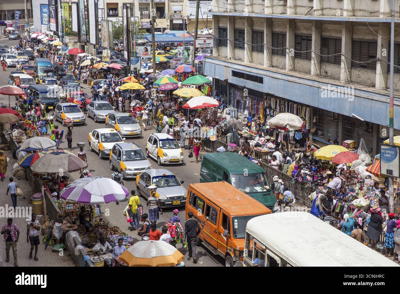 Accra, Ghana - 27 maggio 2017: Vista di una vivace scena di strada, un vivace arazzo di ombrelli colorati, taxi gialli e persone vicino al mercato di Makola, vive di commercio e movimento. Foto Stock