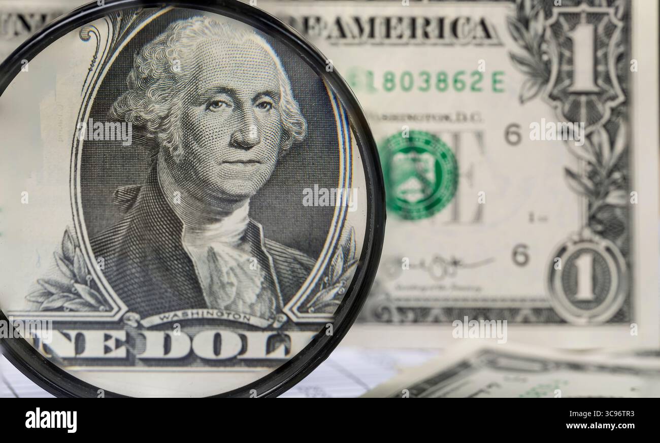 Banconote e matita in dollari americani attraverso una grande lente d'ingrandimento Foto Stock